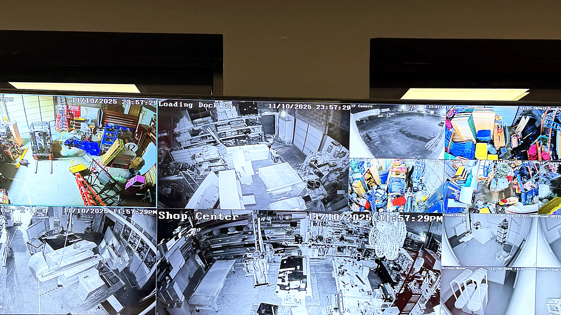 A large display showing a live multi-camera surveillance grid with dozens of tiles, mounted in an office.