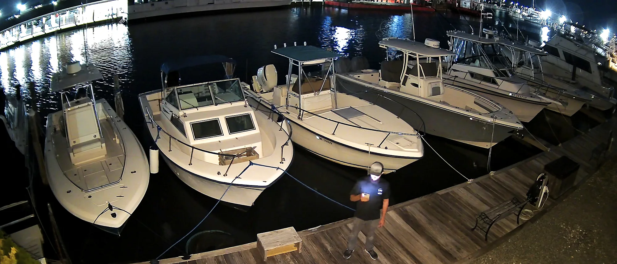A night image captured by an installed camera showing boats in a marina slip, timestamped on screen and legible in near darkness.