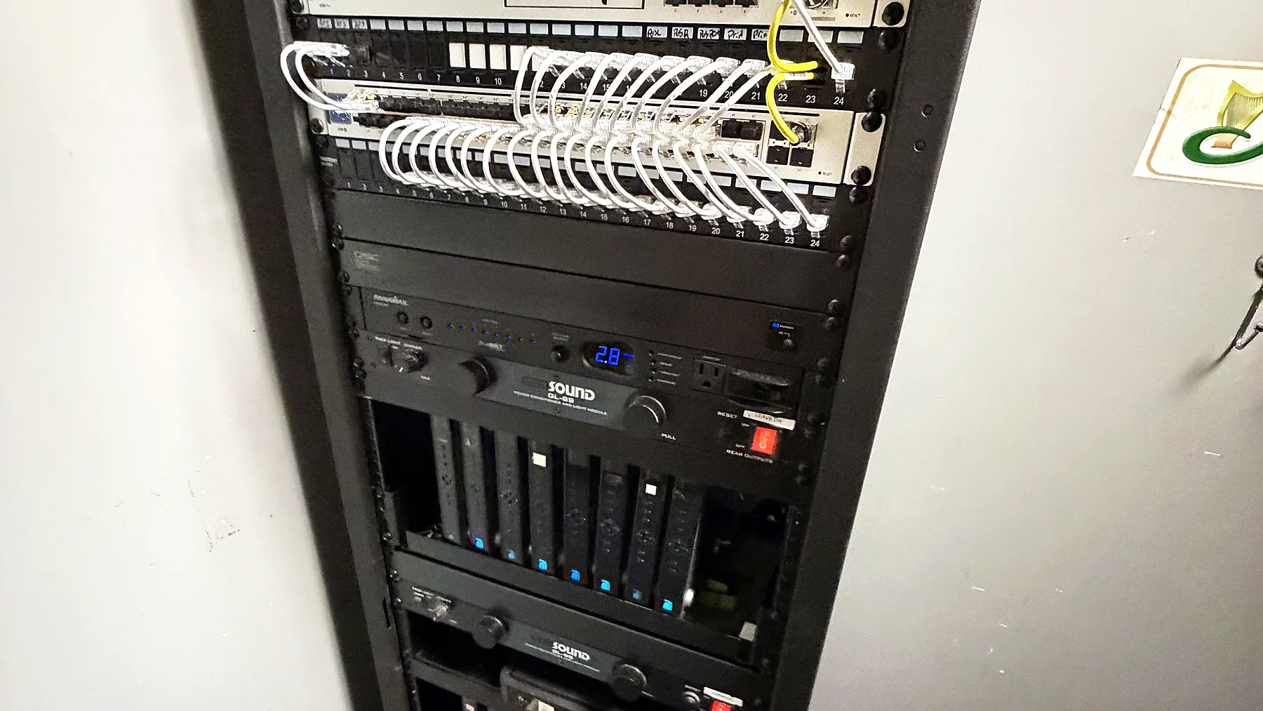 A floor-standing equipment rack with a white patch field routed through horizontal cable management, network and audio-visual equipment stacked below.