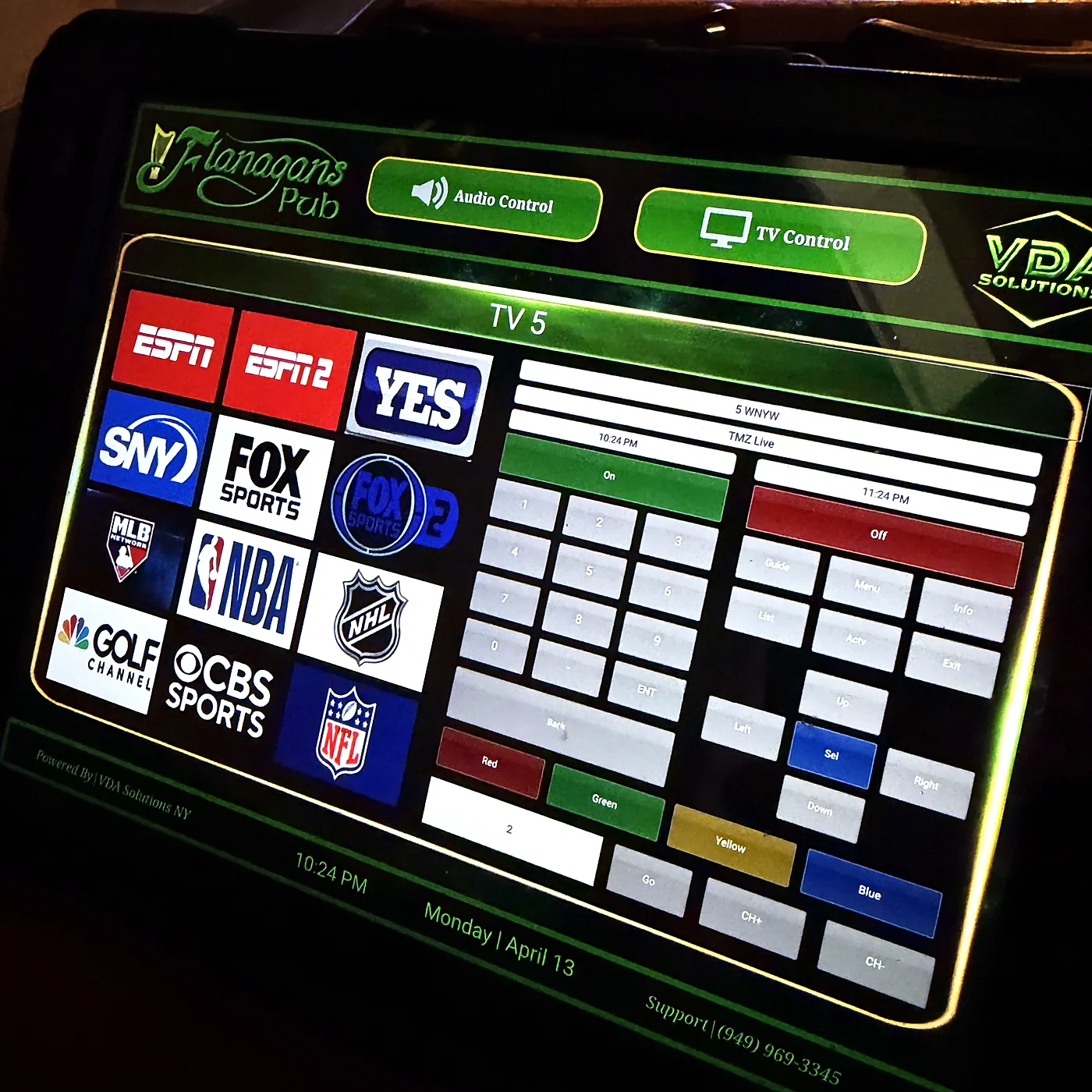 A touch panel showing a custom interface listing sports networks and a per-television source selection grid.